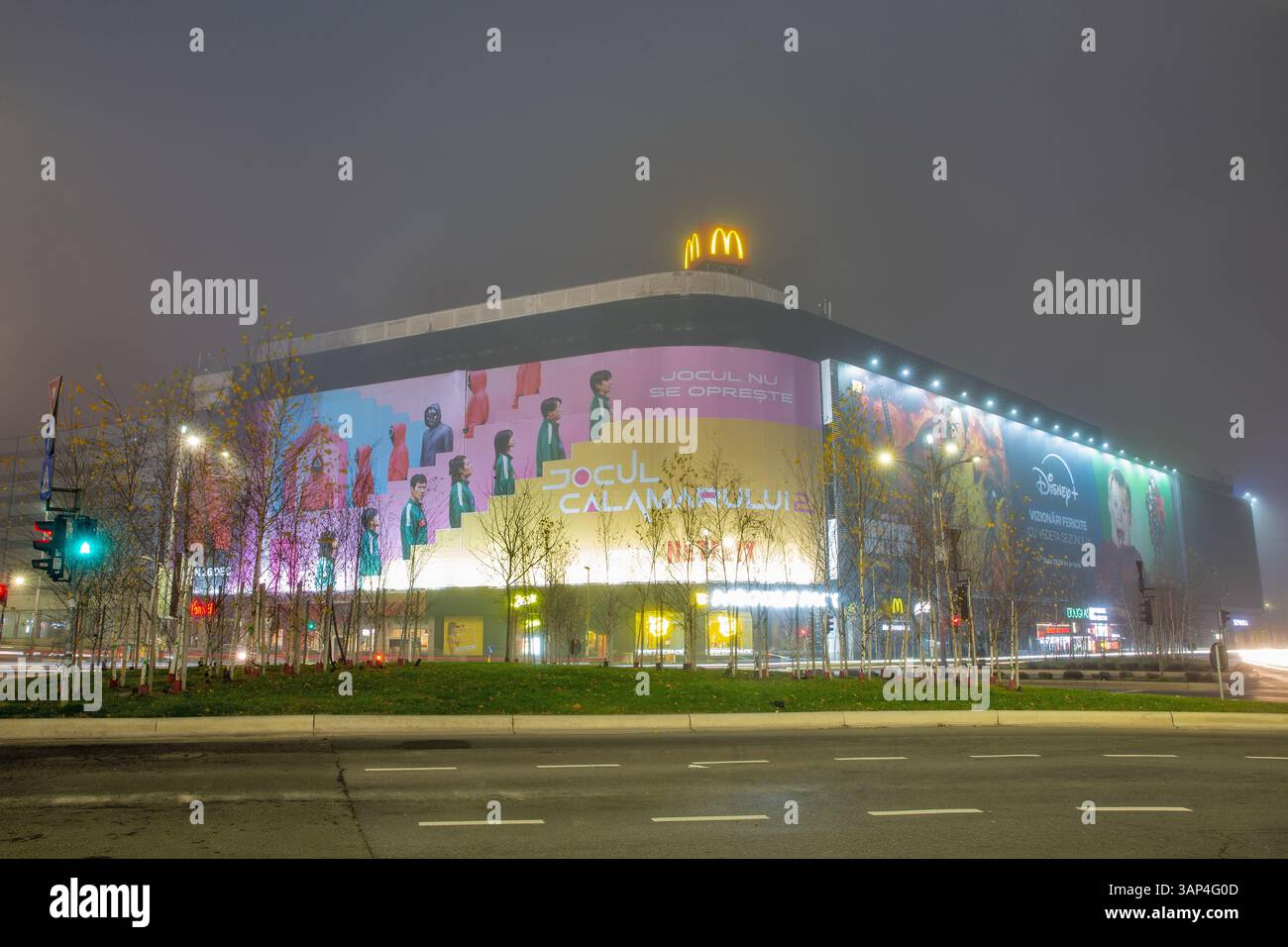 Bucarest, Roumanie - 31 décembre 2024 : Centre commercial Unirea avec publicité McDonalds sur la rue nocturne du centre-ville Banque D'Images