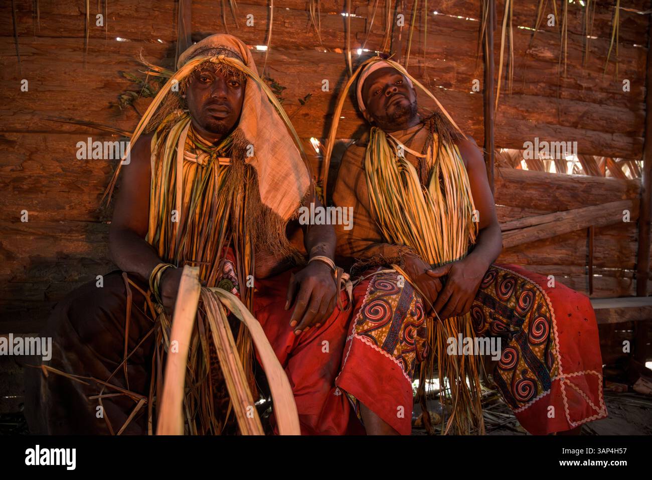 Participants à une cérémonie Bwiti, vêtus d'une tenue rituelle faite de feuilles de palmier séchées, après une séance toute la nuit. Banque D'Images