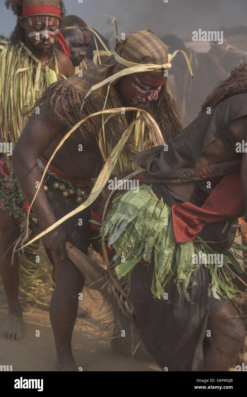 Les danseurs vêtus d'une tenue de cérémonie traditionnelle dansent devant le temple où ils ont tenu une cérémonie de Bwiti toute la nuit. Banque D'Images