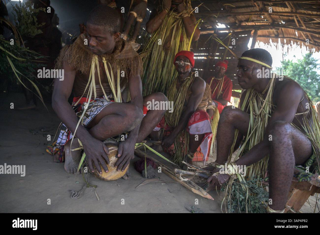Les batteurs vêtus d'une tenue de cérémonie traditionnelle jouant les tom-Toms devant le temple où ils ont tenu une cérémonie de Bwiti toute la nuit. Banque D'Images
