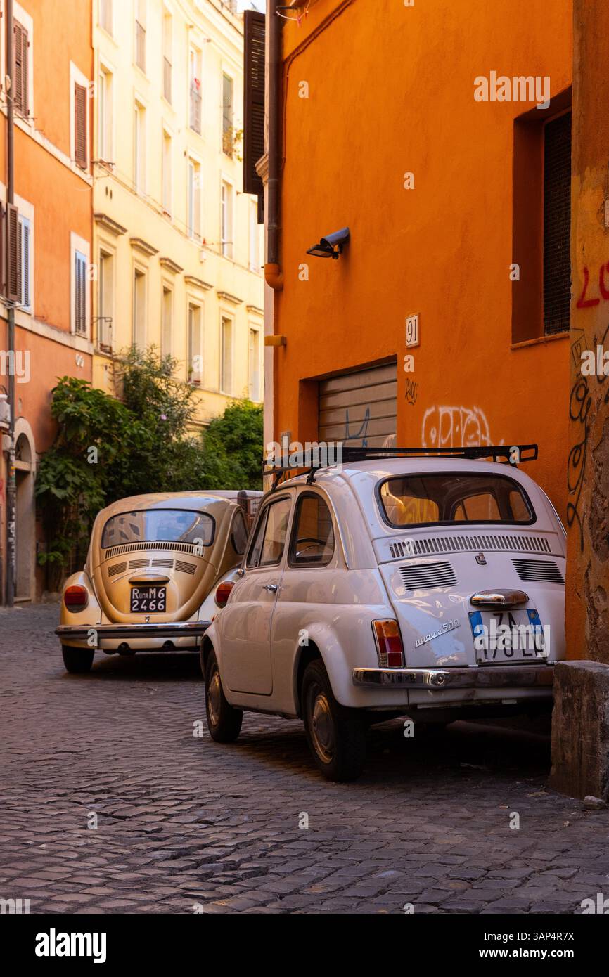Vintage Fiat 500 et VW Beetle garé dans une rue étroite et colorée de Rome, Italie. Voitures européennes classiques dans un cadre urbain. Banque D'Images