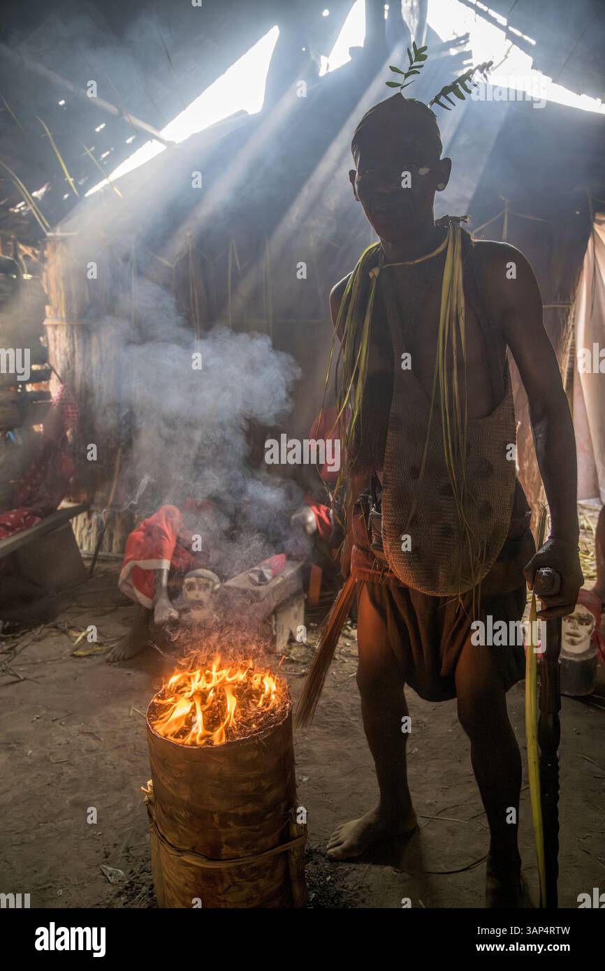 Portrait d'un homme près du feu sacré, vêtu d'un costume rituel fait de feuilles de palmier séchées, après une cérémonie Bwiti toute la nuit. Banque D'Images
