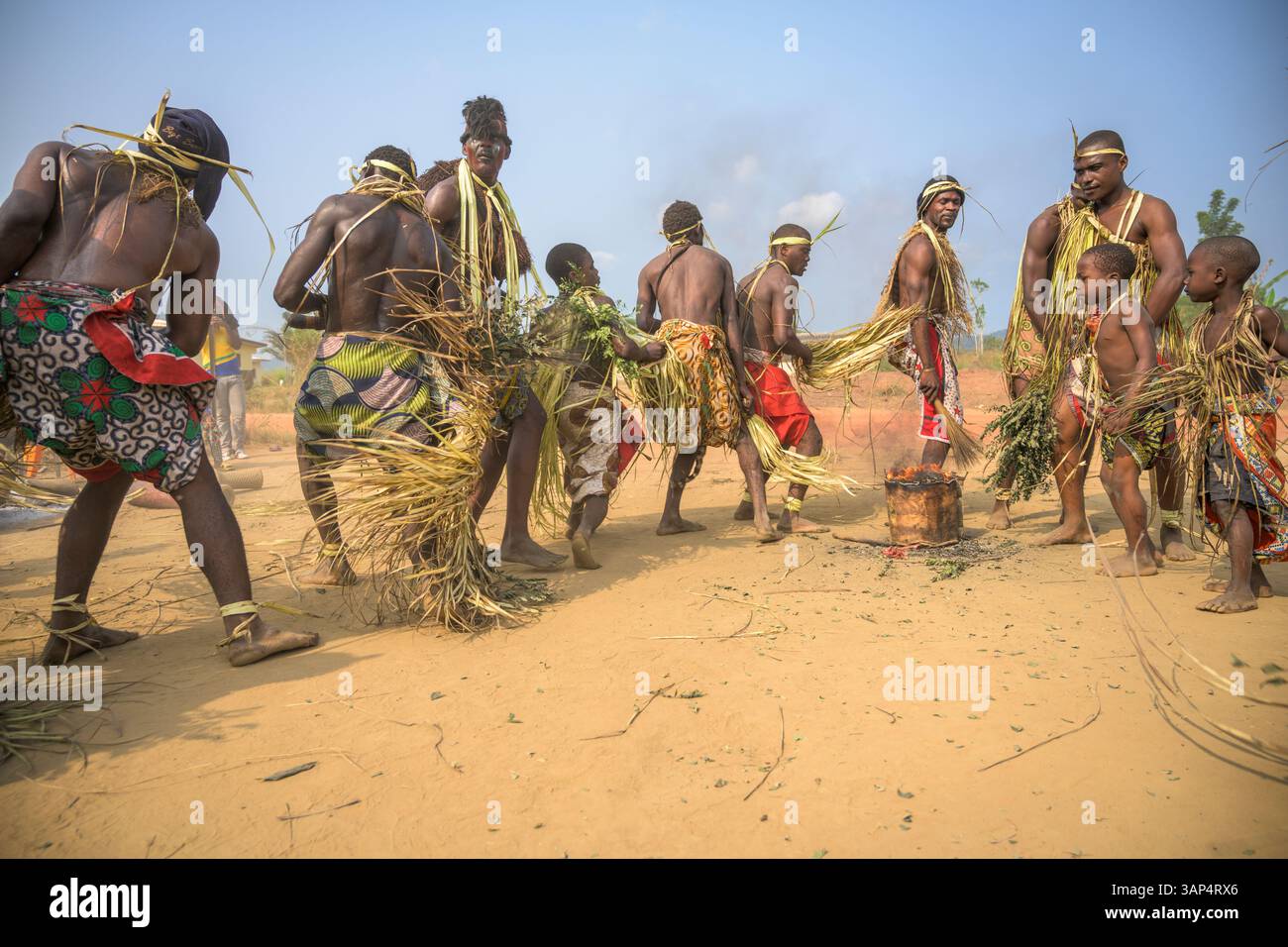 Les danseurs vêtus d'une tenue de cérémonie traditionnelle dansent le matin devant le temple où ils ont tenu une cérémonie de Bwiti toute la nuit. Banque D'Images