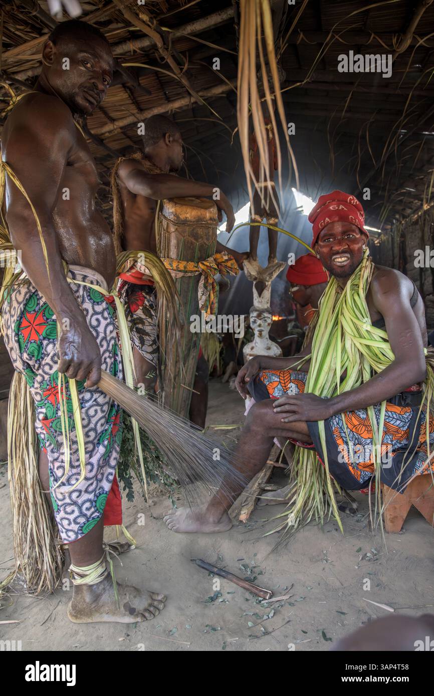Les batteurs vêtus d'une tenue de cérémonie traditionnelle jouent les tom-Toms devant le temple où ils ont tenu une cérémonie de Bwiti toute la nuit. Banque D'Images