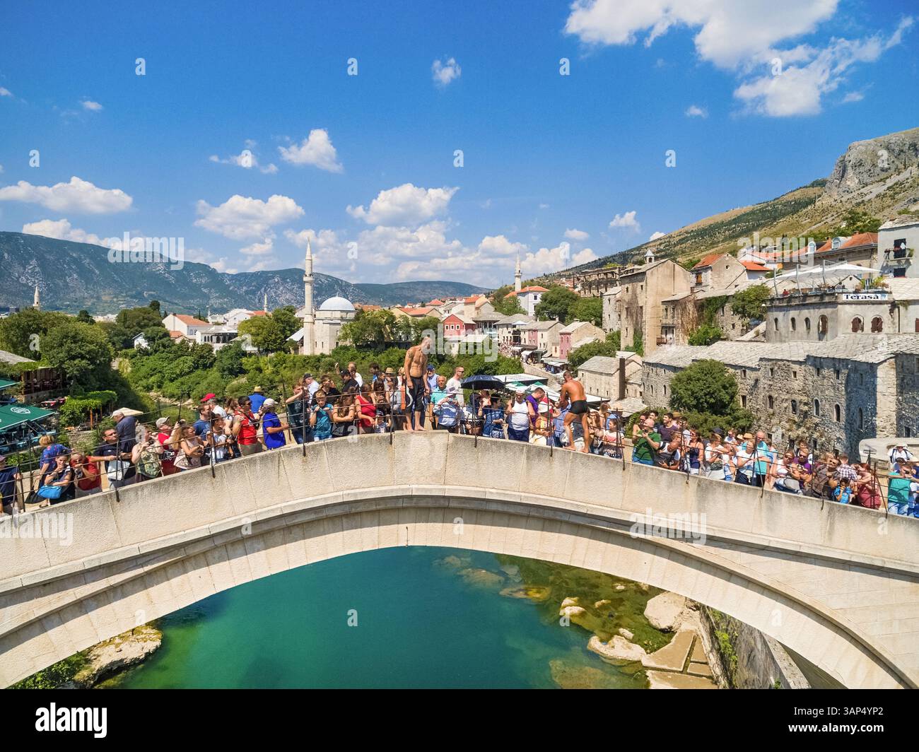MOSTAR, BOSNIE-HERZÉGOVINE - 10 AOÛT 2016 : deux gars entourés de touristes qui se préparent à sauter dans la rivière Neretva depuis Old Bridge. Banque D'Images