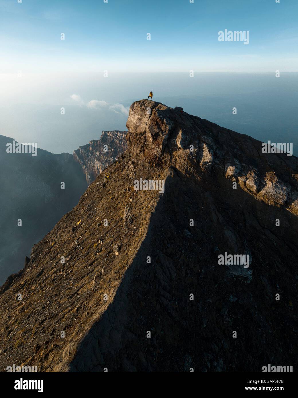 Vue aérienne d'une personne au sommet du mont Agung au coucher du soleil, un volcan sur l'île de Bali, Indonésie. Banque D'Images