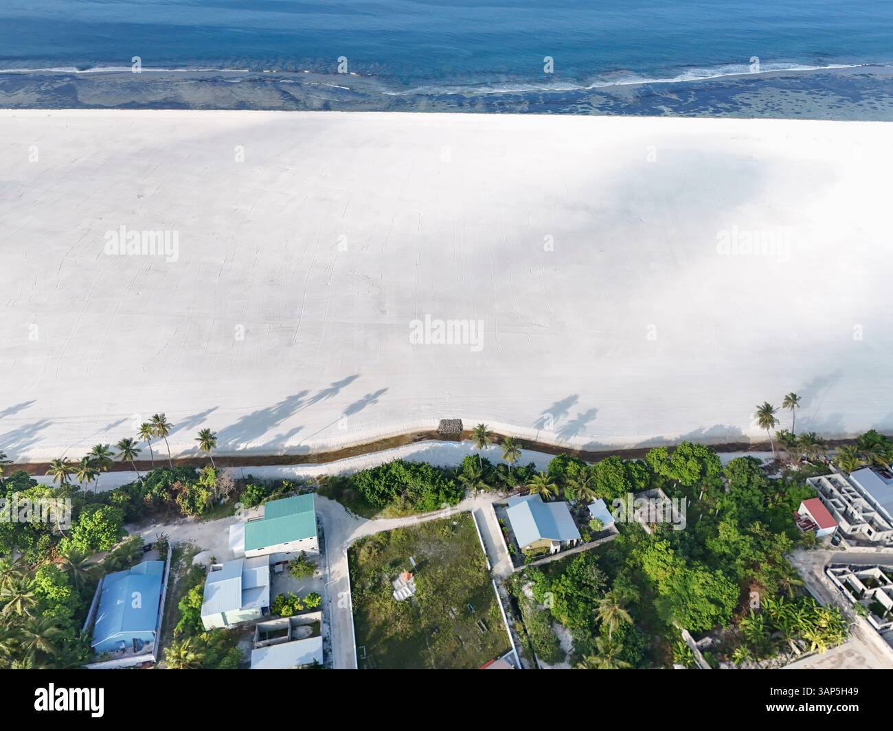 Vue aérienne de la récupération artificielle avec des palmiers, du sable et des maisons, Maradhoo, Maldives. Banque D'Images