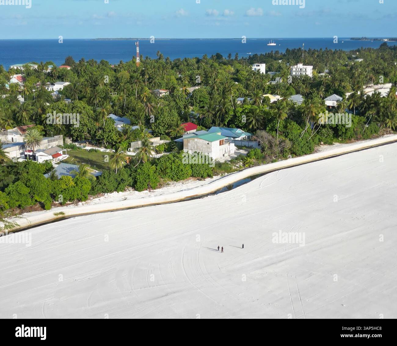 Vue aérienne de la station balnéaire tropicale avec des palmiers, des maisons et des gens, Maradhoo, Addu Atoll, Maldives. Banque D'Images