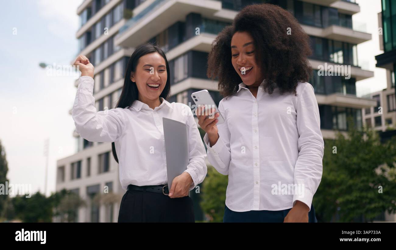 Afro-américaine asiatique les femmes coréennes lisent téléphone mobile smartphone bonne nouvelle victoire victoire victoire approbation atteindre succès femmes d'affaires collègues Banque D'Images