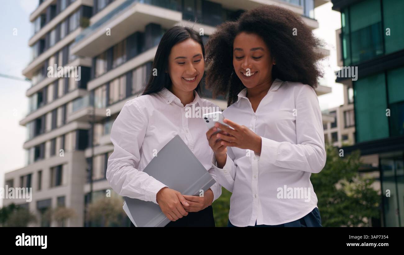 Afro-américaine asiatique coréenne femmes collègues femmes d'affaires entreprises utilisant le téléphone mobile smartphone en ligne discuter parler des médias sociaux Banque D'Images
