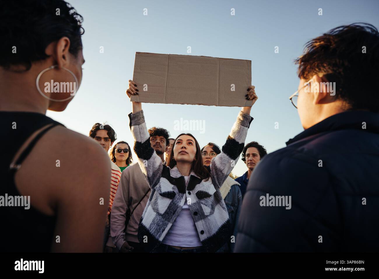 Un groupe diversifié de personnes participant à une manifestation pacifique, tenant un panneau blanc pour leur cause. Le groupe fait preuve d'unité et de détermination, avec un Banque D'Images