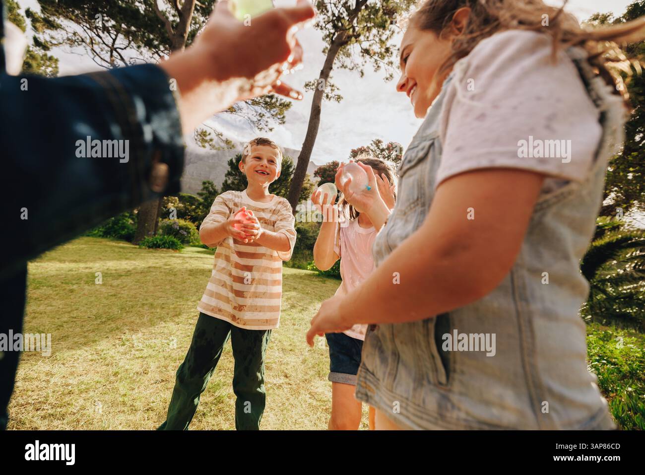 Groupe d'enfants profitant d'une journée d'été amusante jouant avec des ballons d'eau à l'extérieur dans un parc. Capte le bonheur et la convivialité lors de l'outdoo jeune Banque D'Images