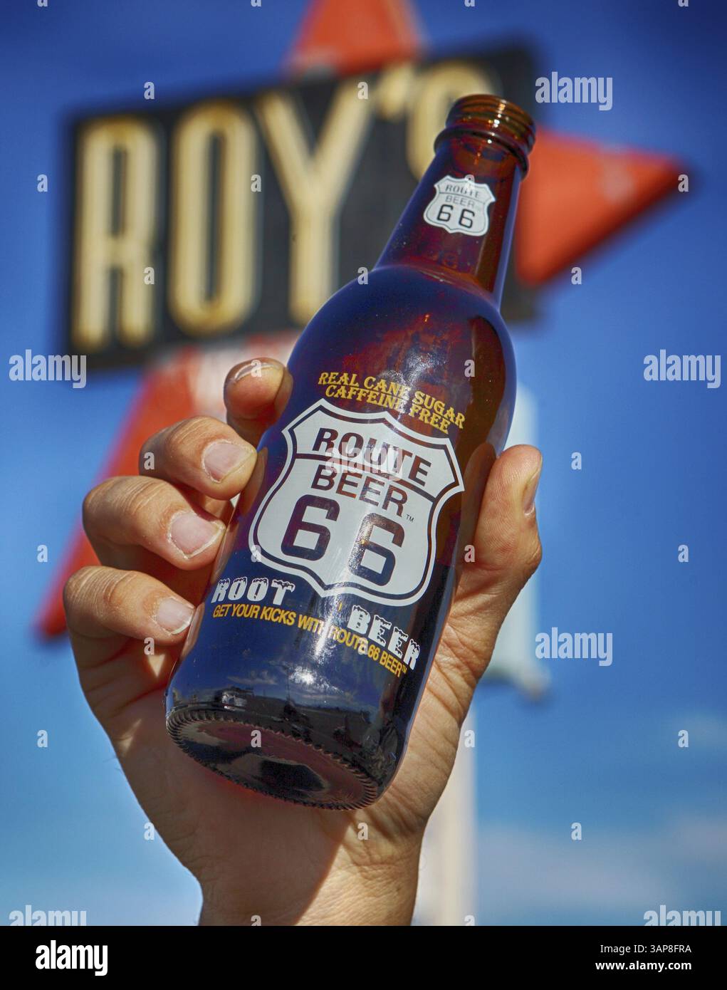 Un homme tient une bouteille de bière racine devant un panneau de motel Banque D'Images