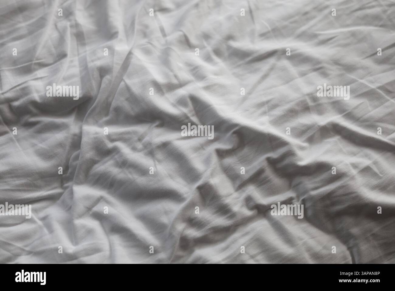 Draps de lit froissés et blancs avec de nombreux plis Banque D'Images