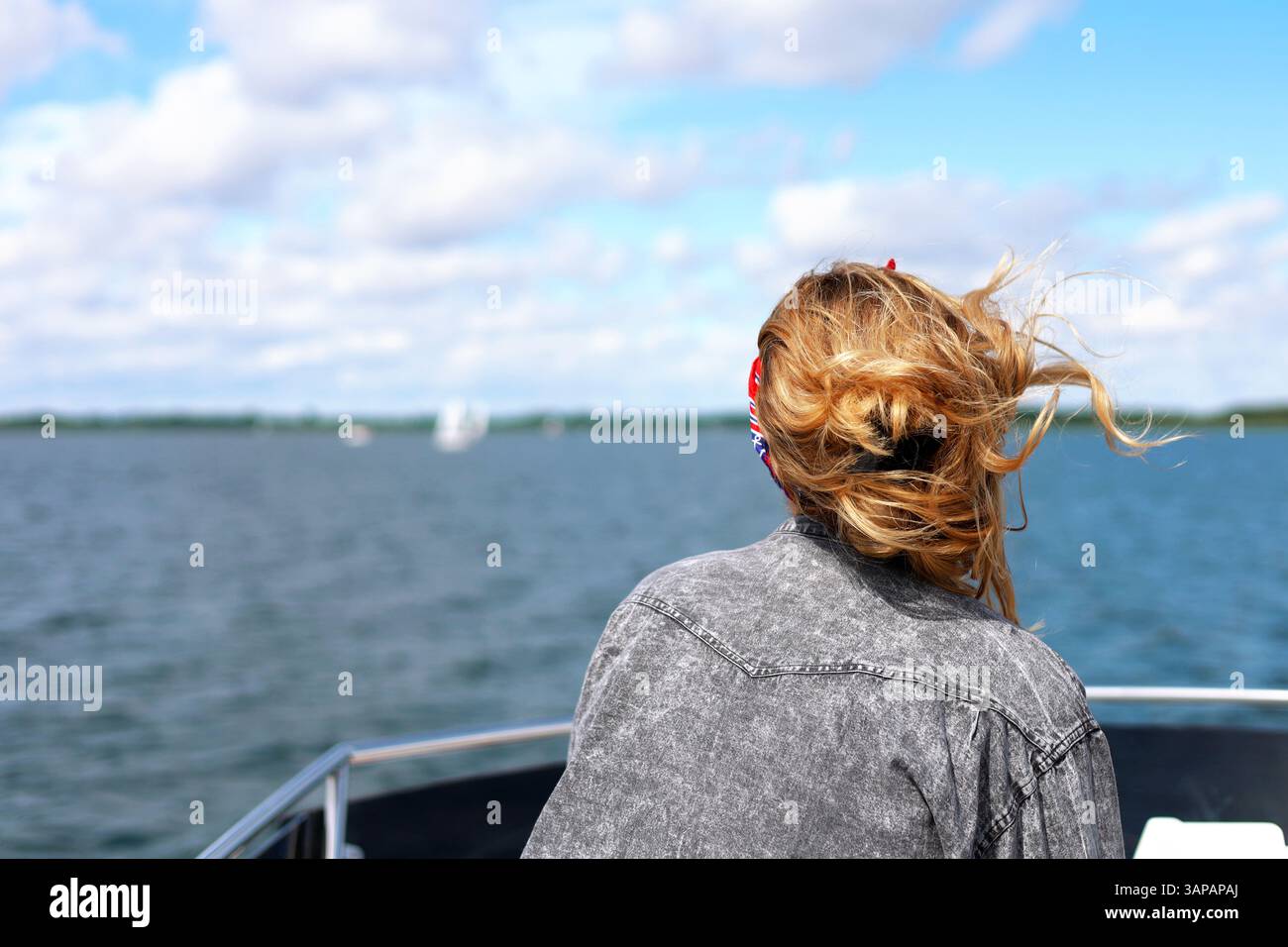 Belle fille blonde backshot sur un toit de bateau de luxe regardant au loin, cheveux coulant sur le vent, voiliers en arrière-plan Banque D'Images Belle fille blonde backshot sur un toit de bateau de luxe regardant au loin, cheveux coulant sur le vent, voiliers en arrière-plan Banque D'Images