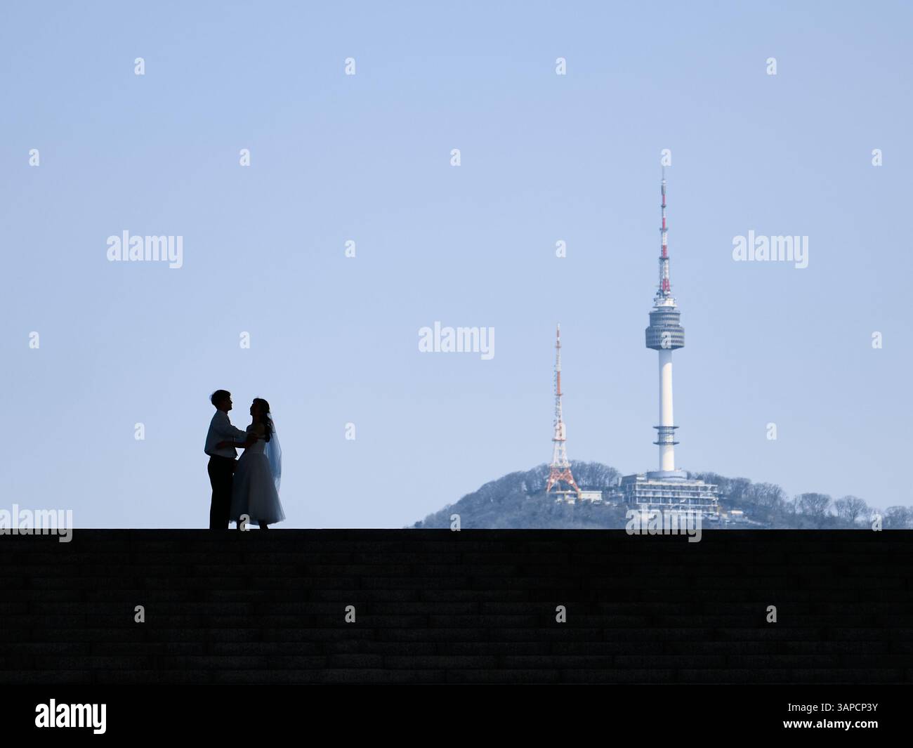Une silhouette romantique d'une mariée et mariée avec l'emblématique Tour Namsan (N Seoul) de Séoul en arrière-plan, symbolisant l'amour et l'engagement dans le cœur Banque D'Images
