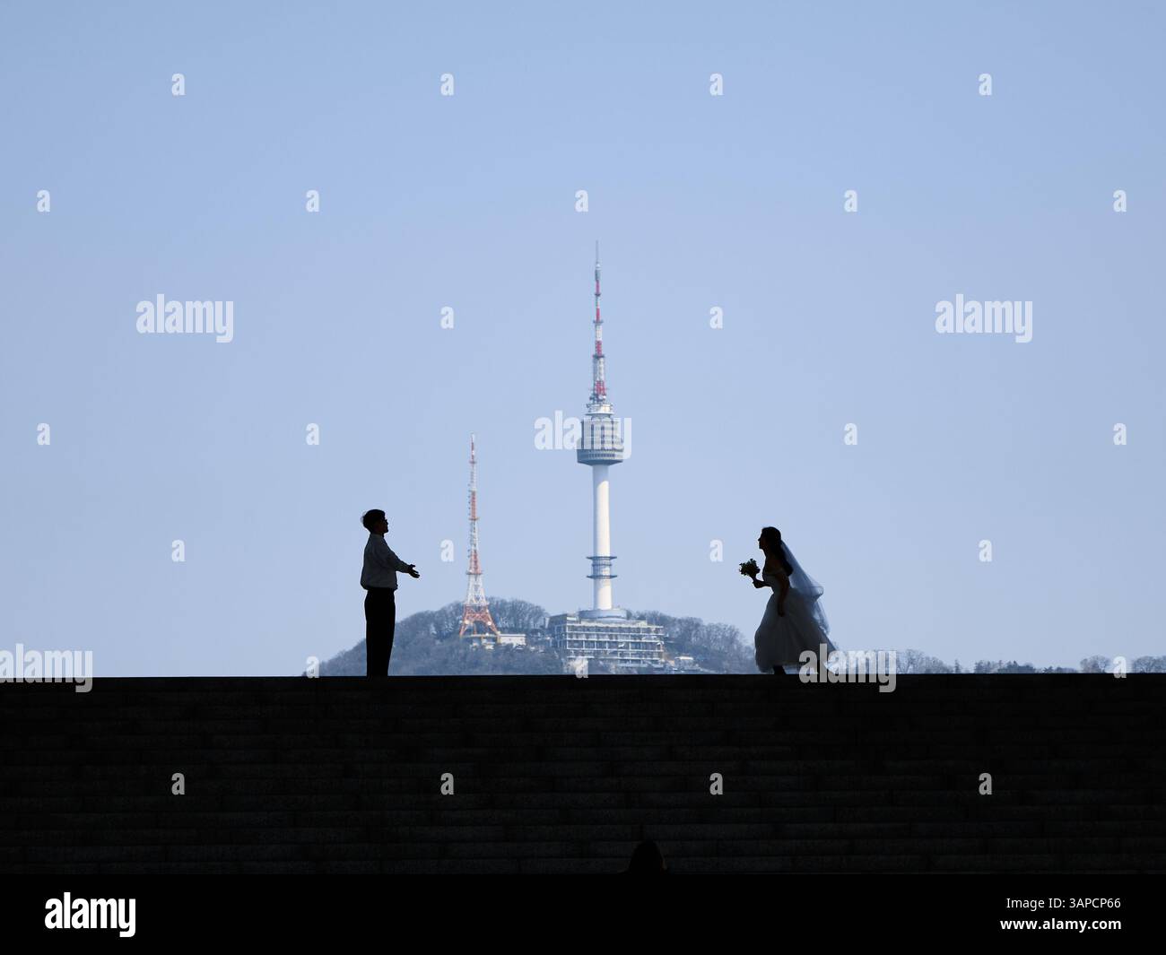 Une silhouette romantique d'une mariée et mariée avec l'emblématique Tour Namsan (N Seoul) de Séoul en arrière-plan, symbolisant l'amour et l'engagement dans le cœur Banque D'Images