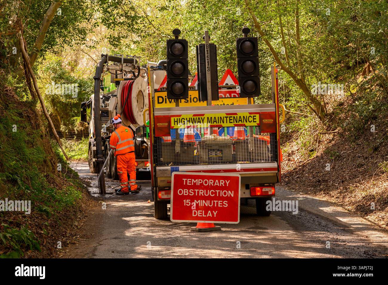 Entretien de la route fermeture temporaire de la voie de campagne pendant que les travailleurs vident les drains de bord de route avec un tuyau d'eau à haute pression dans la campagne de l'est du Sussex, en Angleterre. Banque D'Images
