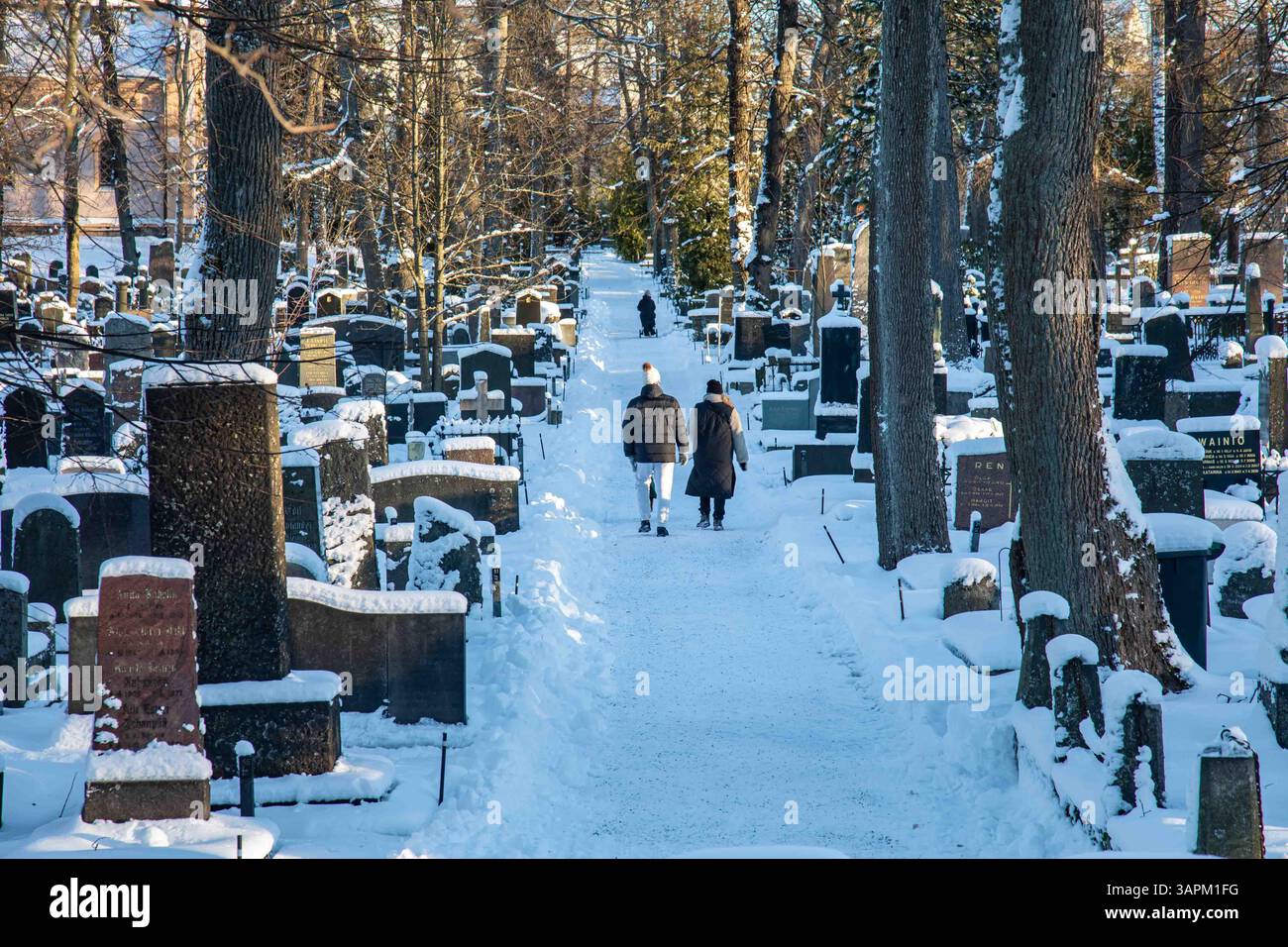 Les gens se promènent dans le cimetière enneigé de Hietaniemi par une journée ensoleillée d'hiver à Helsinki, en Finlande Banque D'Images