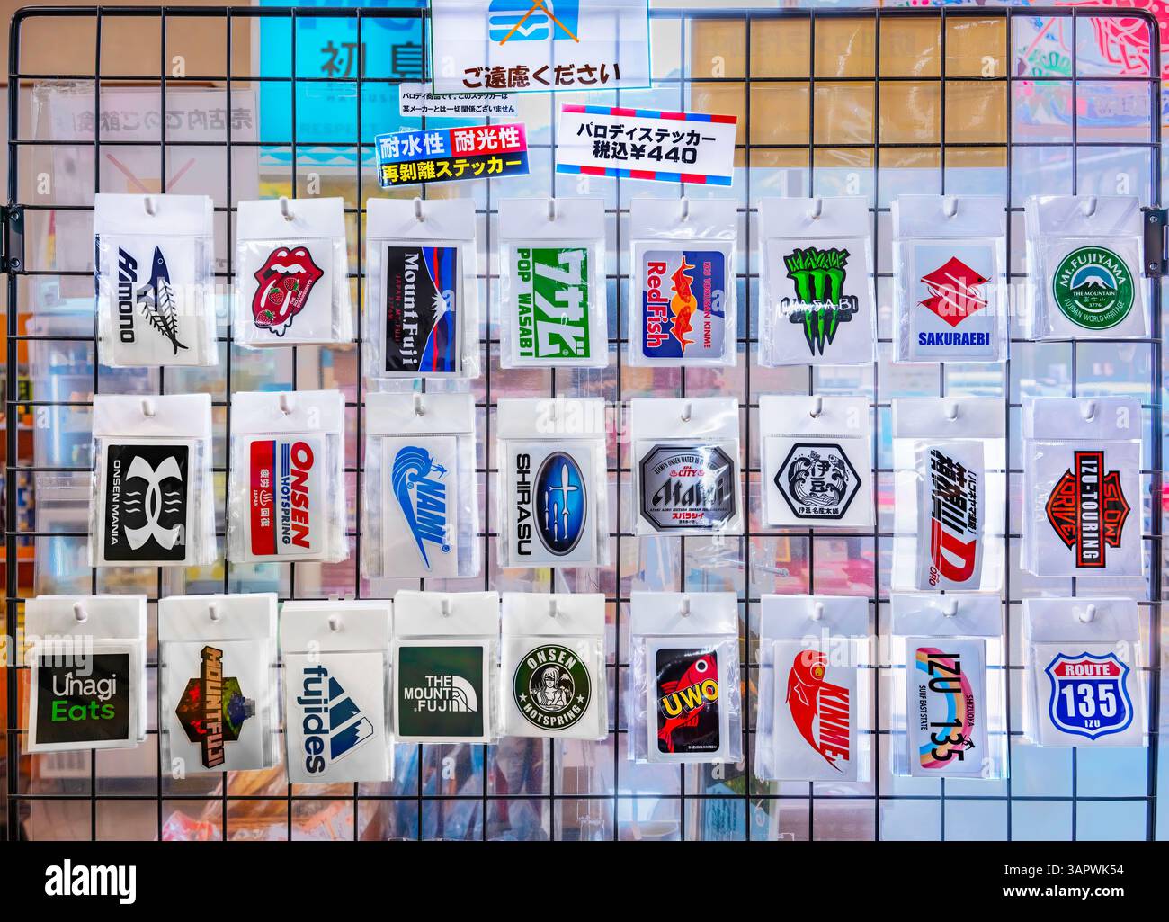 japon, tokyo - mars 25 2025 : des autocollants de parodie japonais imperméables et amovibles des logos de marques célèbres dans le monde entier sont affichés sur une grille dans une boutique, application Banque D'Images