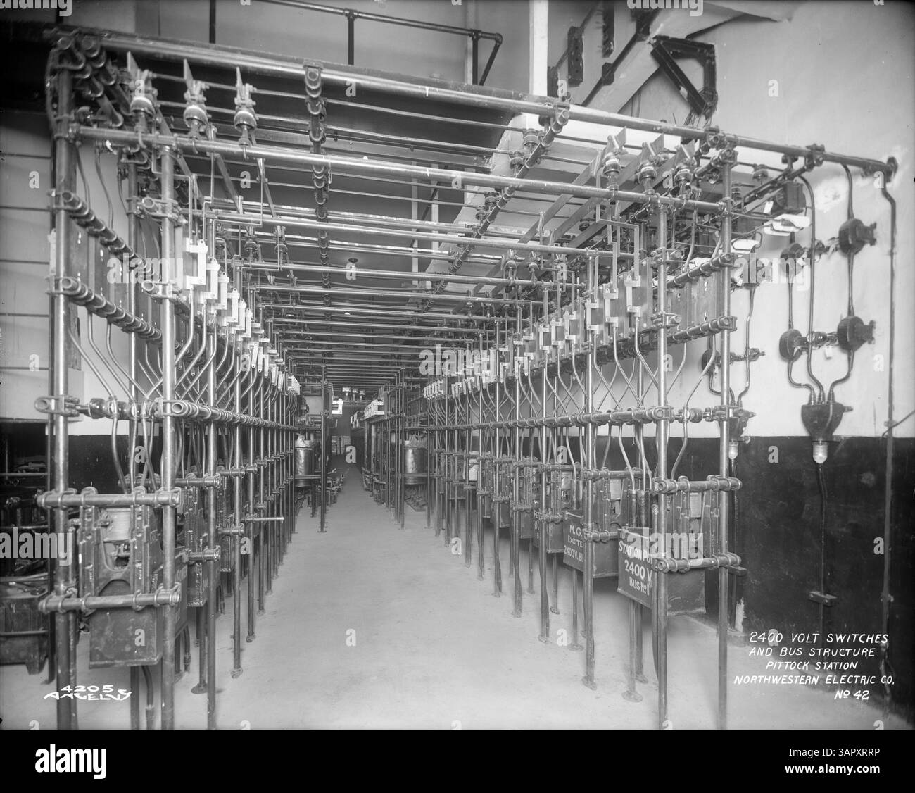 Photographie montrant une vue intérieure d'interrupteurs de tension et d'équipement électrique à la station Pittock à Portland, Oregon. L'image montre des tuyaux et des boîtes métalliques, avec des interrupteurs visibles étiquetés avec des informations électriques. Banque D'Images