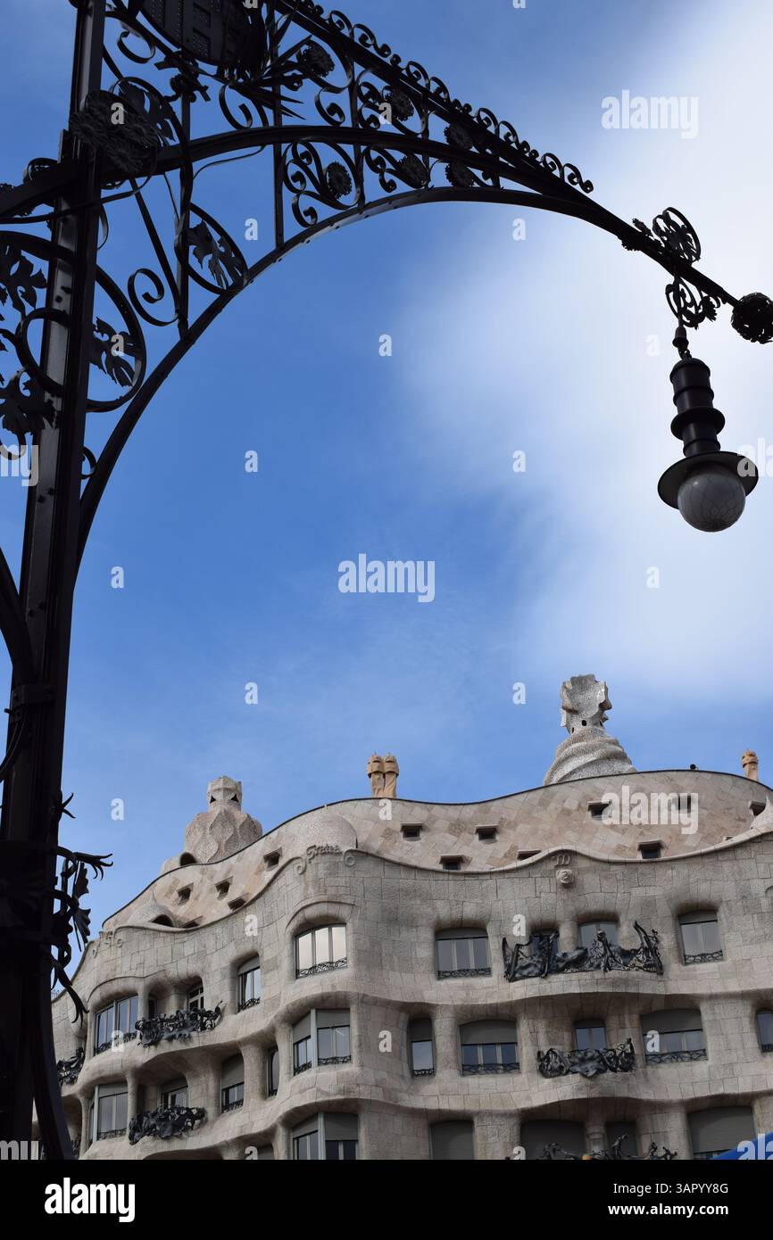 Vista de la Pedrera (Casa Milà) en Barcelona, una joya arquitectónica de Gaudí, con farola modernista enmarcando el cielo azul del Eixample Banque D'Images