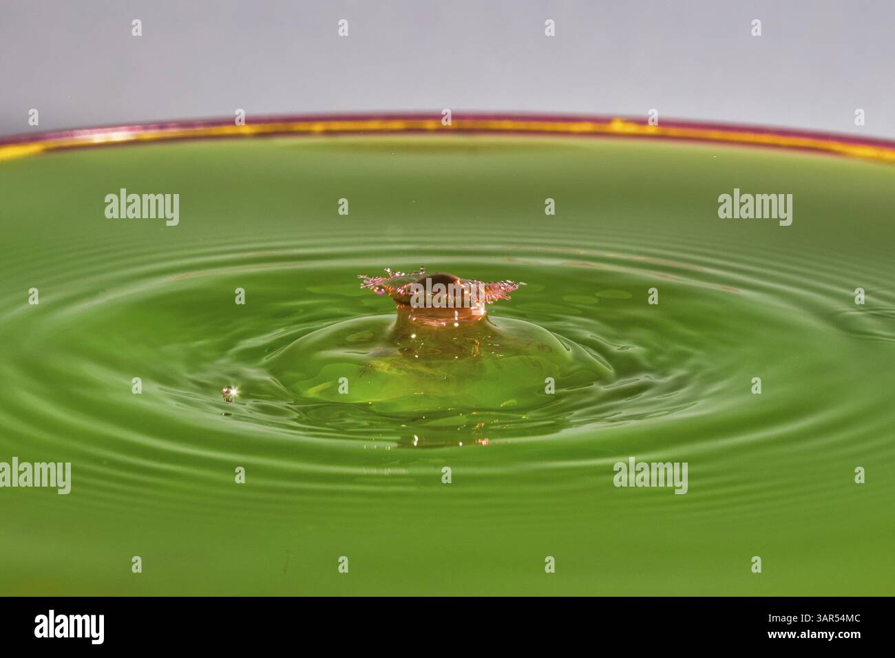 Un cube brun s'élève doucement au-dessus du liquide vert, gouttelettes d'eau, collision, photographie à grande vitesse, concept, chiffres de l'eau Banque D'Images