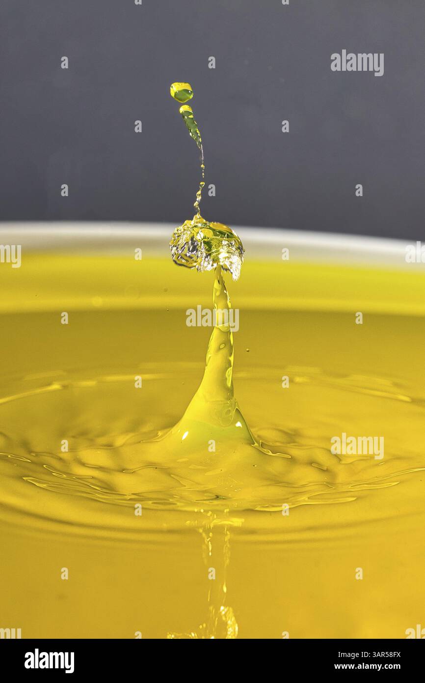 La gouttelette d'eau jaune vif s'élève, crée des éclaboussures vives et reflète la lumière ambiante, gouttelette d'eau, collision, photographie à grande vitesse, concept, w Banque D'Images