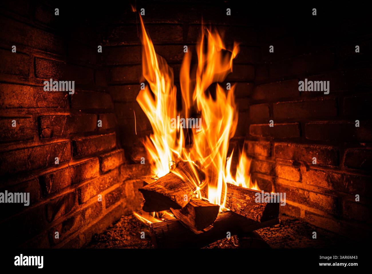 Flammes de bois de chauffage brûlant brillamment dans un foyer en brique Banque D'Images