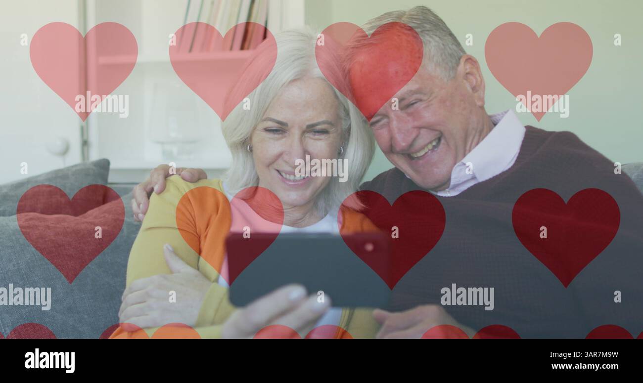 Image d'icônes de cœur de médias sociaux sur un couple de personnes âgées utilisant un smartphone Banque D'Images