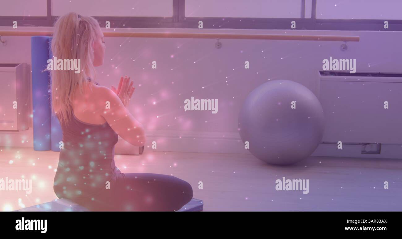 Image de taches lumineuses sur une femme caucasienne pratiquant le yoga et méditant Banque D'Images