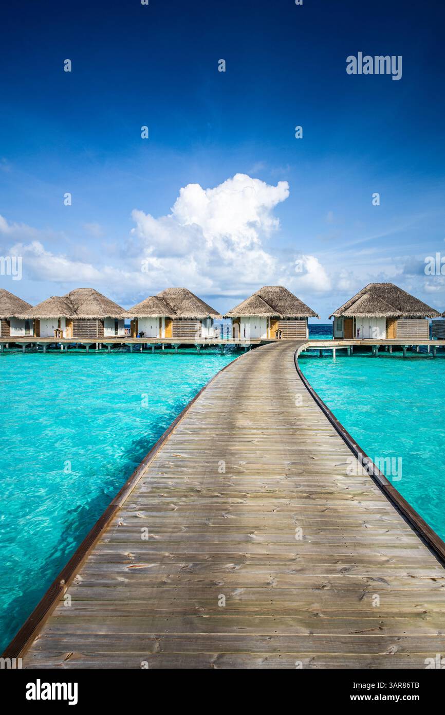 Luxueuses villas aquatiques Maldives avec jetée en bois, vue sur l'océan. Escapade de rêve sur une île tropicale. Arrière-plan de destination de voyage d'été. Bleu ciel ensoleillé mer Banque D'Images