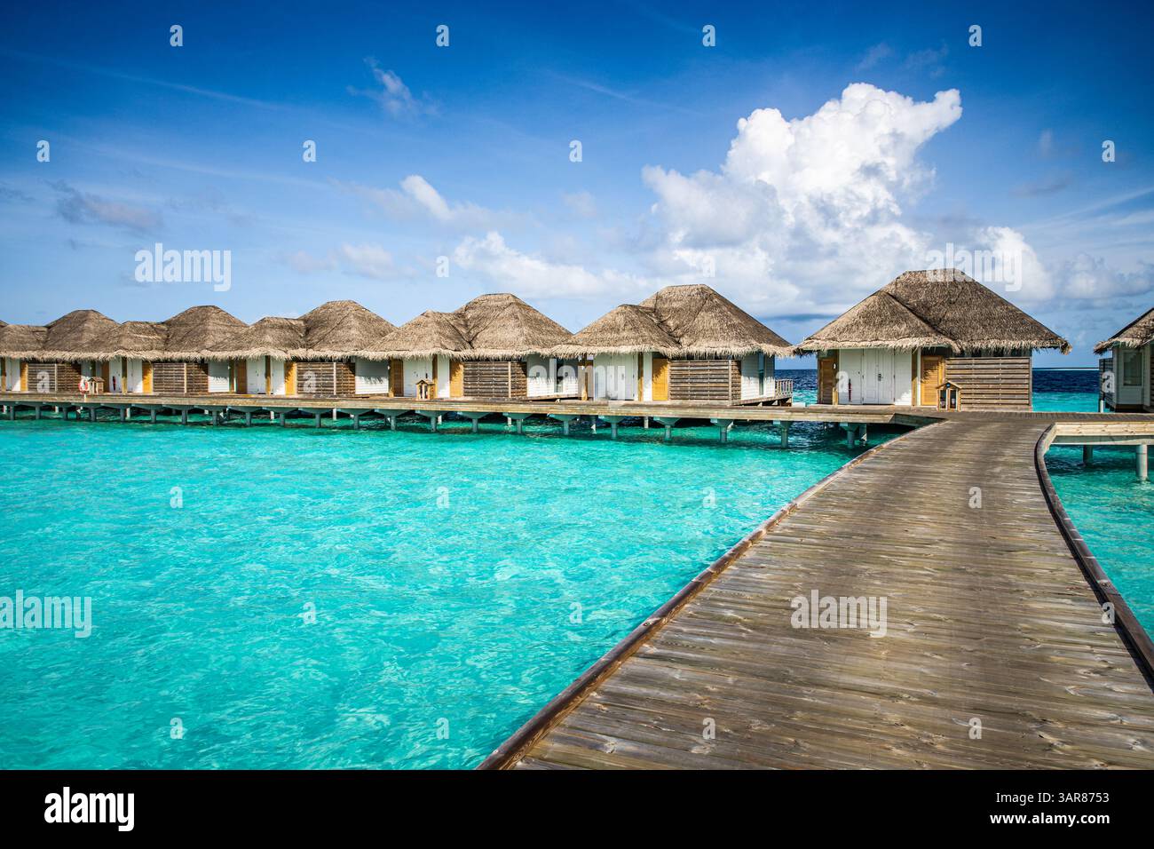 Luxueuses villas aquatiques Maldives avec jetée en bois, vue sur l'océan. Escapade de rêve sur une île tropicale. Arrière-plan de destination de voyage d'été. Bleu ciel ensoleillé mer Banque D'Images