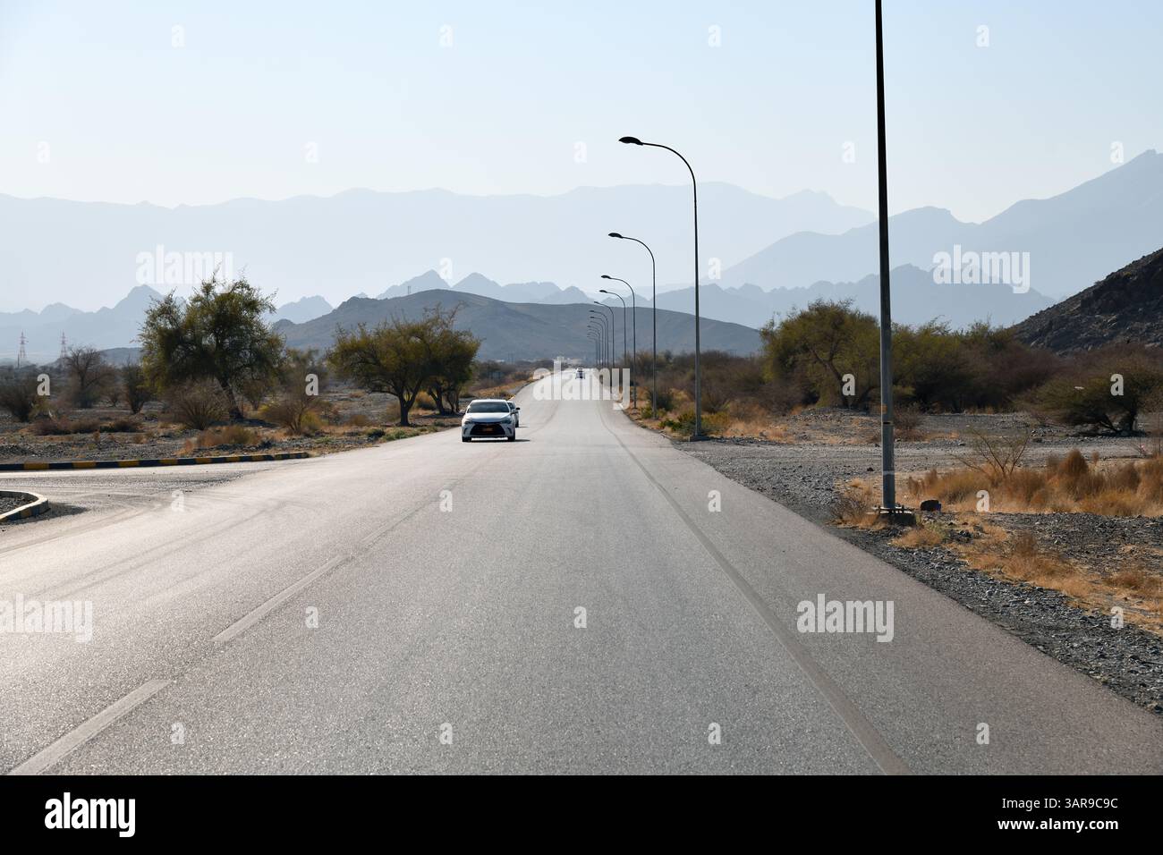 Nizwa, Sultanat d'Oman - 6 avril 2025 : route goudronnée et trafic routier à Oman, montagnes en arrière-plan. Péninsule arabique Banque D'Images