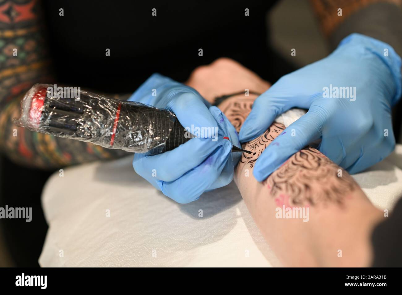 Tatoueur encrant habilement un dessin détaillé sur le bras d'un client Banque D'Images