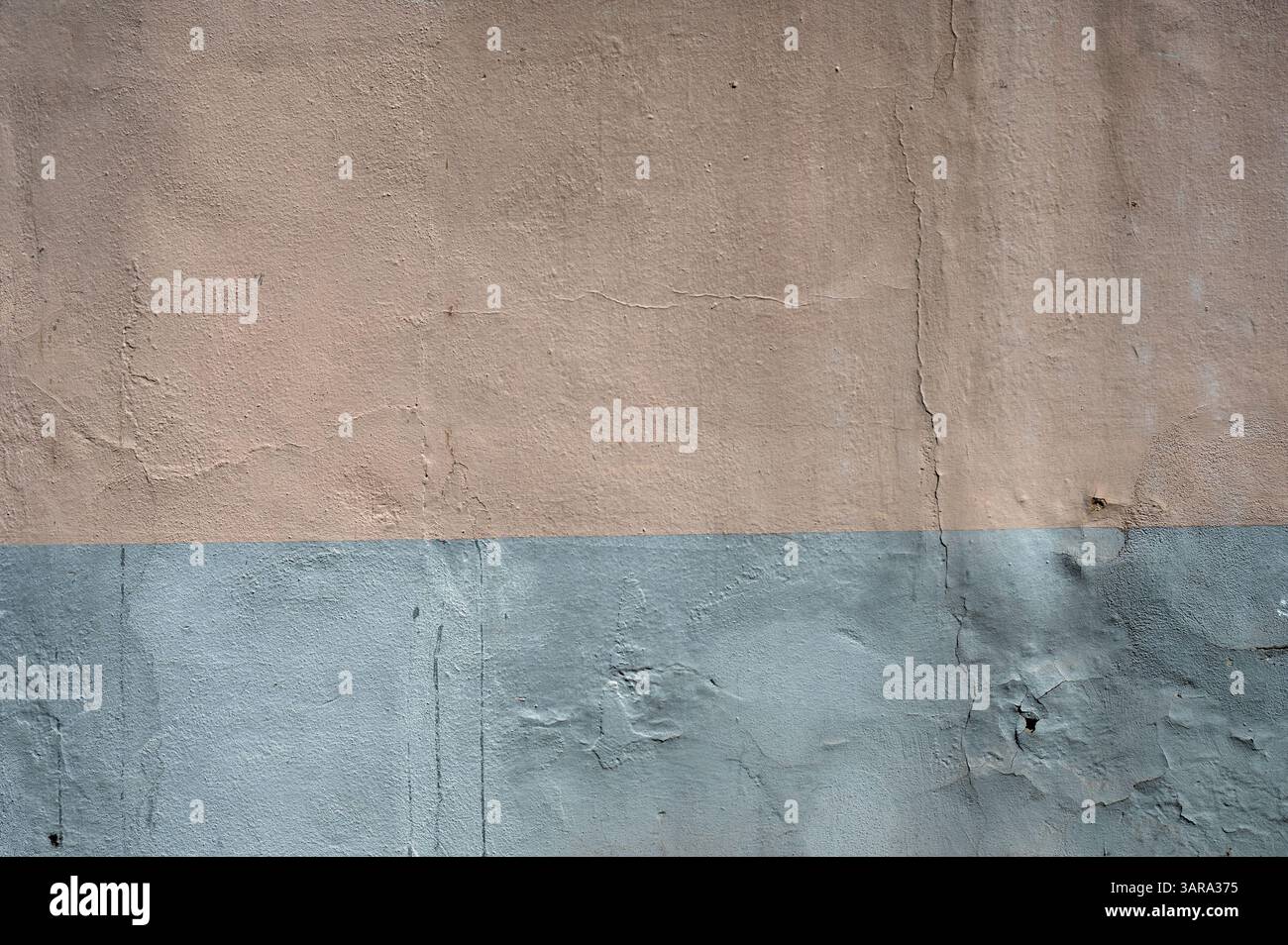 Mur en béton altéré peint en deux tons, beige et gris, présentant un fond texturé idéal pour les projets de conception Banque D'Images
