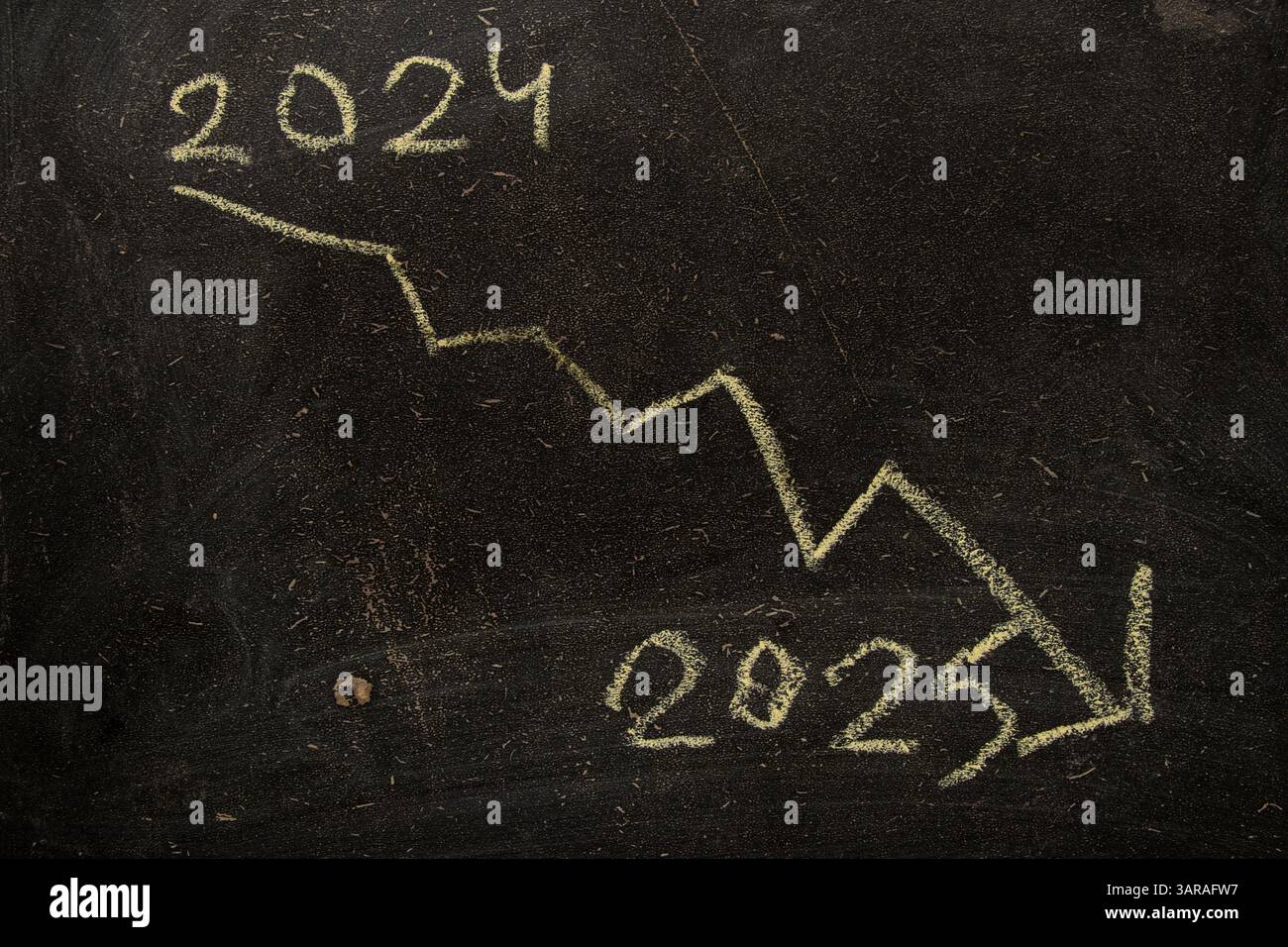 Une flèche descendante de l'année 2024 à l'année 2025 est dessinée sur un tableau noir avec de la craie, crise et récession financière en l'année 2025 Banque D'Images