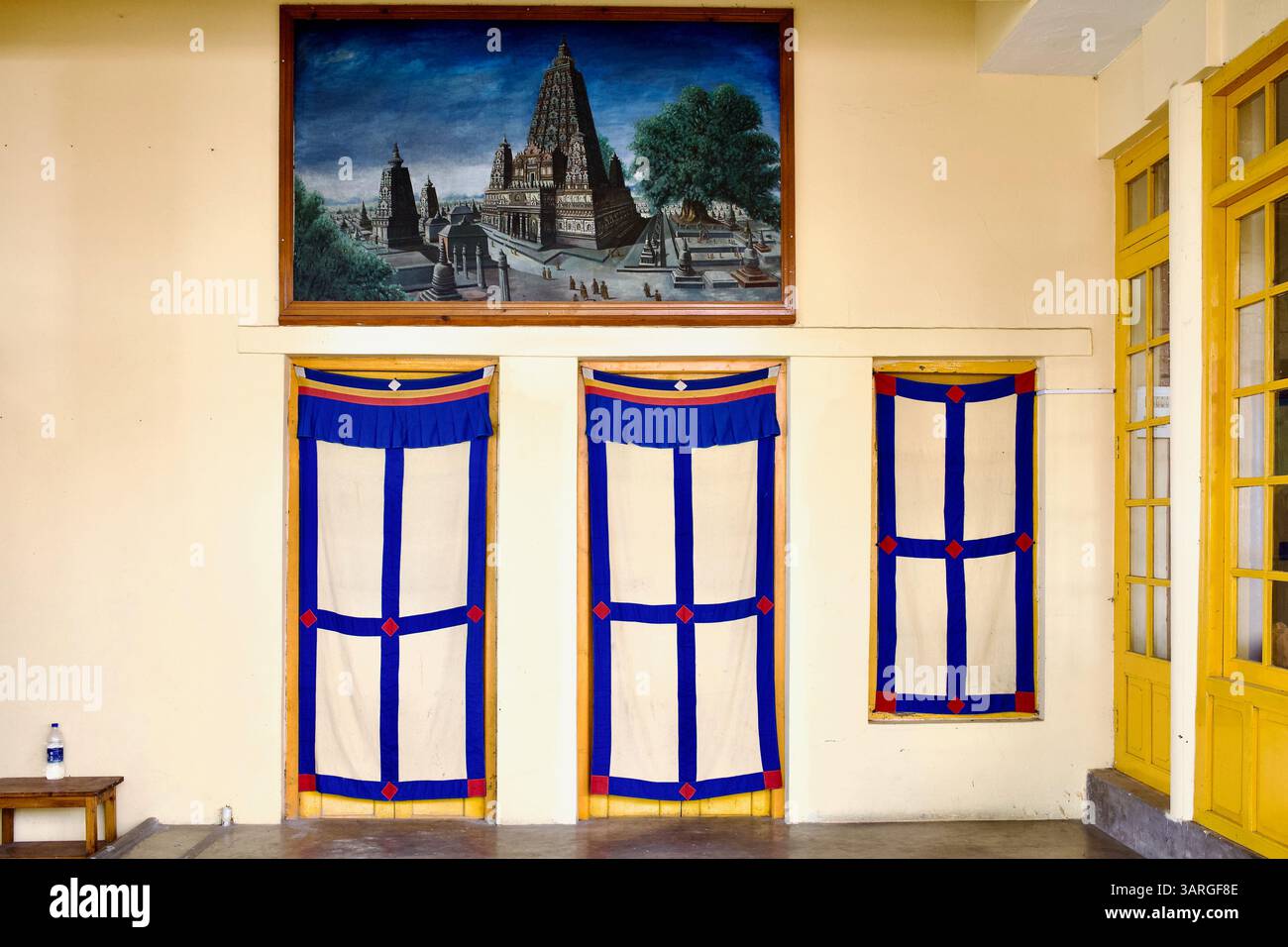 Salle intérieure au temple Dalaï Lama à Dharamshala avec des rideaux de porte tibétains et une peinture de l'arbre Bodhi à Bodh Gaya, Bihar, Inde. Banque D'Images