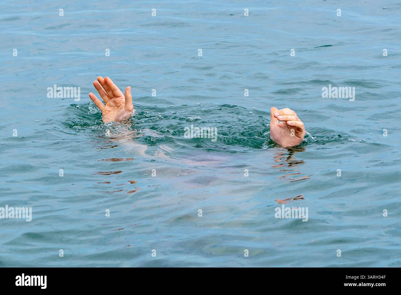 Un homme se noie dans l'eau. Deux mains sortent de l'eau sur le fond des vagues. Concept : personnes noyées, sauvetage d'une noyade pe Banque D'Images