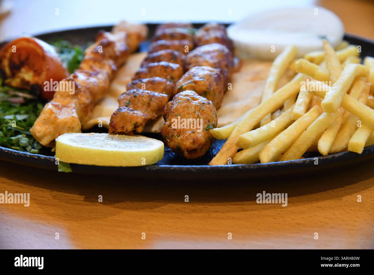 Mishkak. Nourriture populaire à Oman, qui est grillé morceaux de viande marinée, poulet, mouton et bœuf sur de longs bâtonnets de bois avec pommes de terre frites, citron et Banque D'Images
