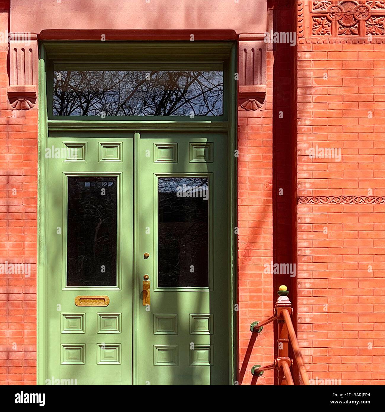 Porte double vert menthe avec panneaux surélevés et fenêtre de tableau arrière sur une façade en briques rouges richement détaillée à Chicago Banque D'Images