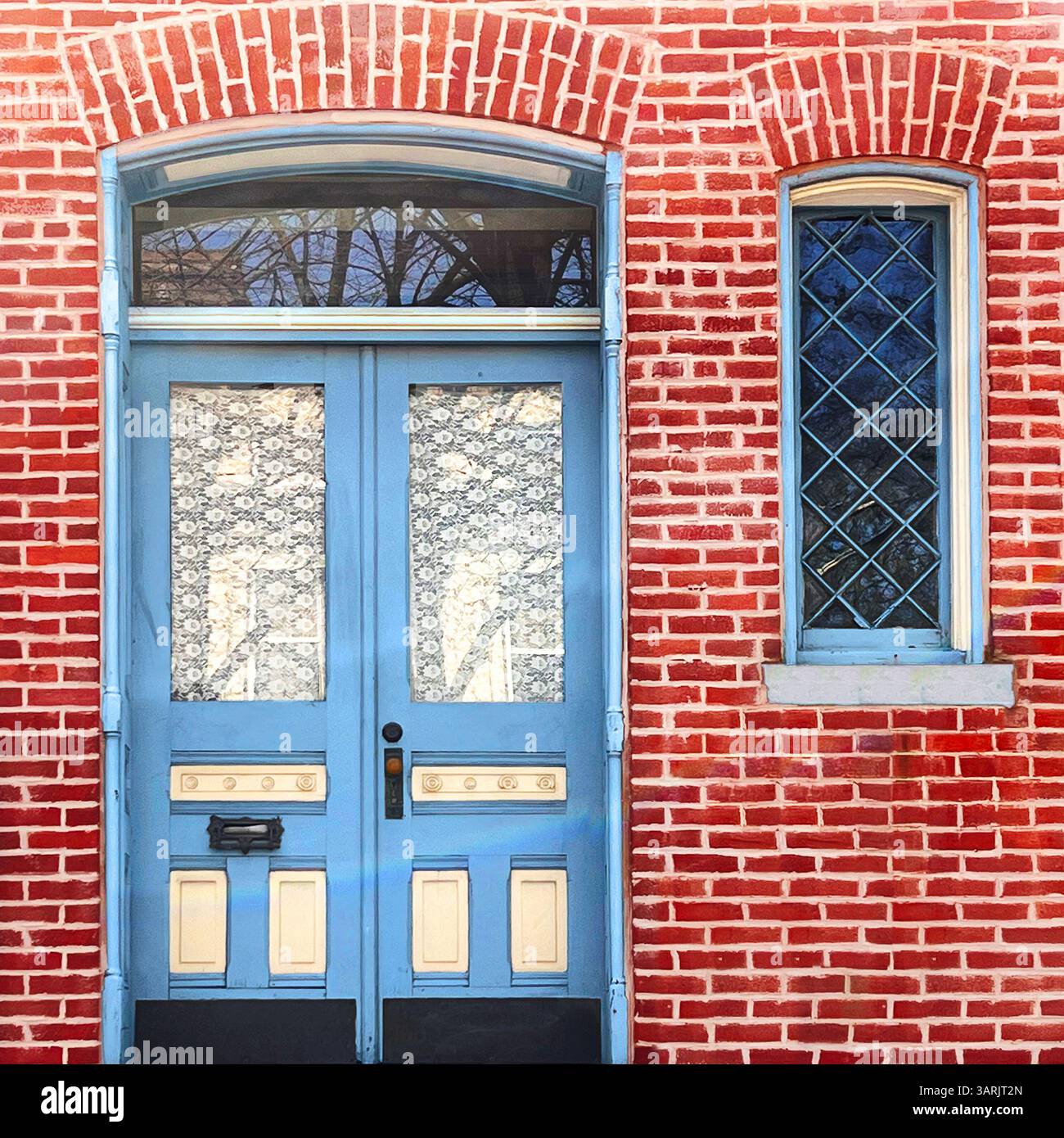 Porte double bleue vintage avec rideaux en dentelle et fenêtre en lambris de losange, située dans une façade en briques rouges vibrantes à Chicago - Image de stock capturée avec un smartphone