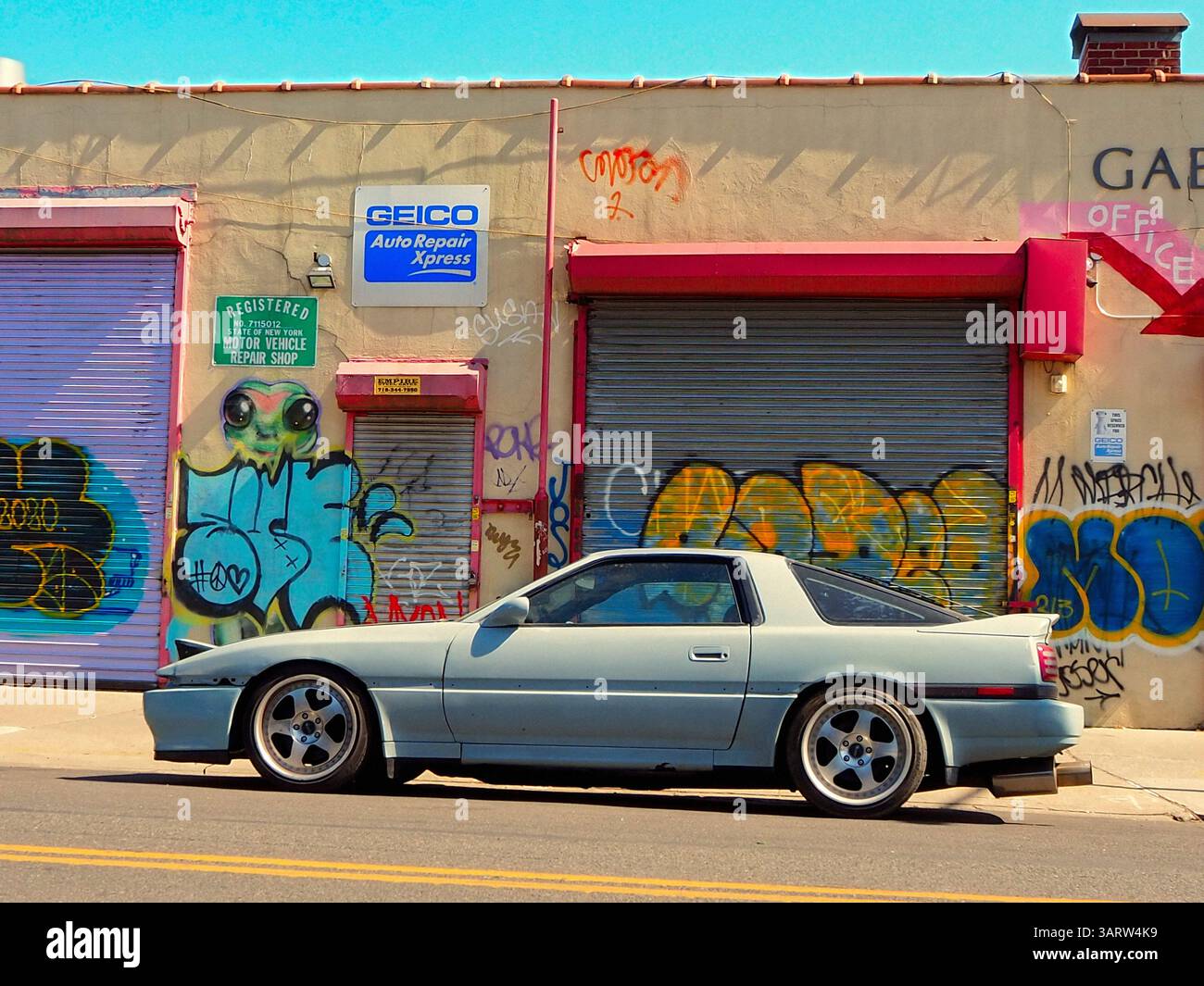 Voiture de sport bleu clair garée devant un mur de graffiti coloré à Williamsburg Brooklyn New York, scène de rue de mai Banque D'Images