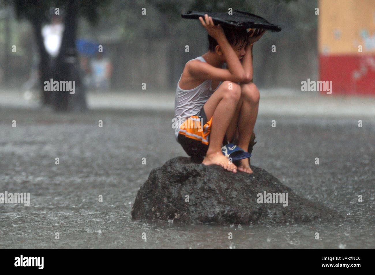 20 août 2013 - Manille, Philippines - Un garçon se réfugie au sommet d'un rocher alors que l'eau monte. Les fortes pluies intensifiées par la tempête tropicale Trami se sont poursuivies pendant un deuxième jour, provoquant une hausse des niveaux d'eau et poussant des milliers de personnes vivant dans les zones basses à fuir leurs foyers. (Crédit image : © Ezra Acayan/ZUMAPRESS.com) Banque D'Images