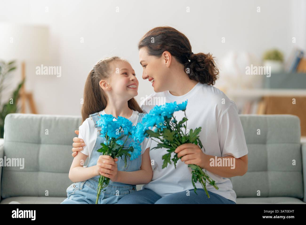 Joyeuse journée des femmes. La fille de l'enfant félicite maman et lui donne des fleurs. Maman et fille souriant et embrassant. Vacances en famille et ensemble. Banque D'Images