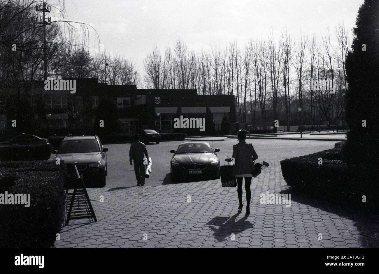 Femme à la mode se dirigeant vers BMW Z-Series Cabriolet après le golf à Pékin, début des années 2000, Pékin, Chine Banque D'Images