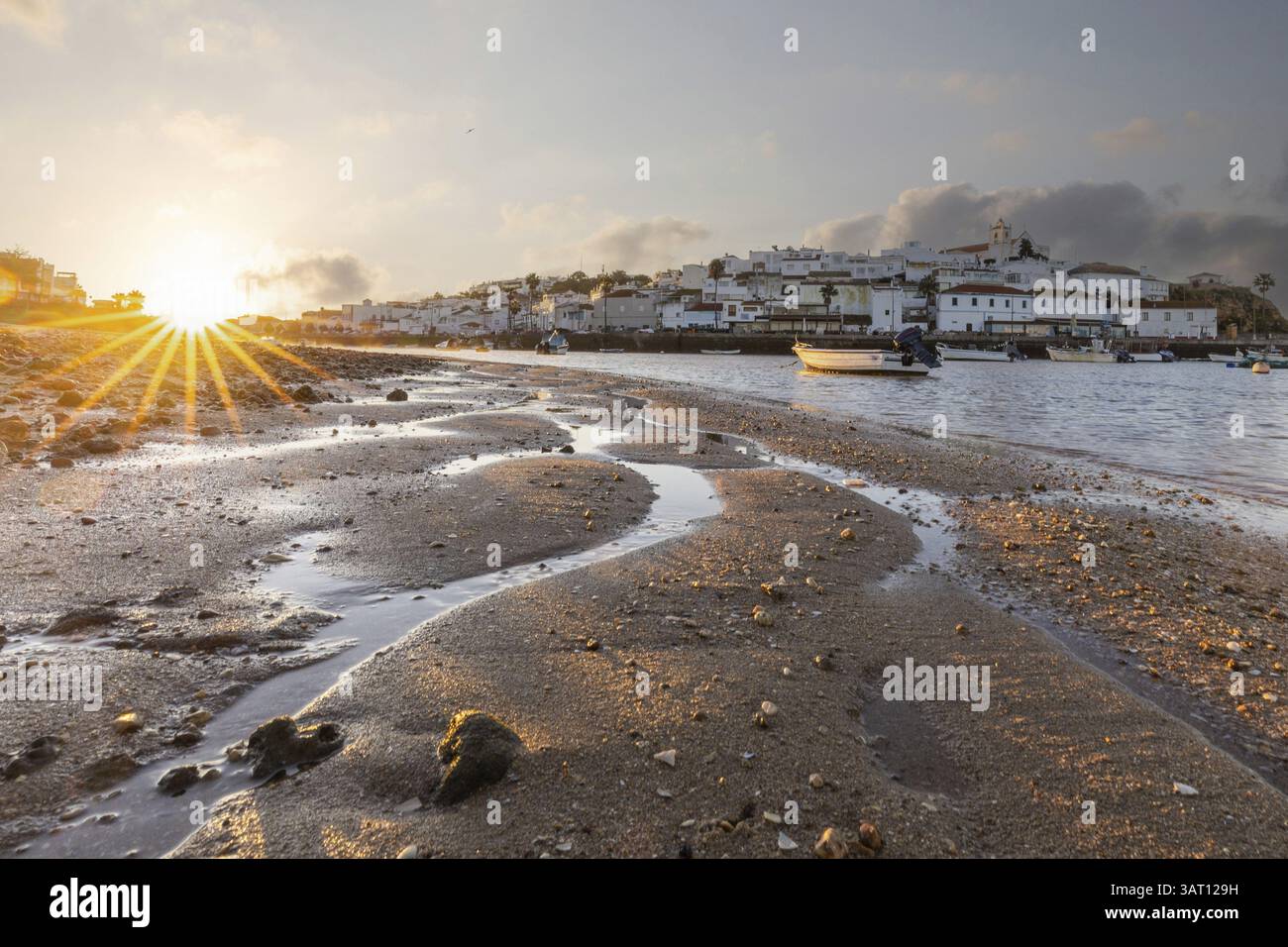 Lever de soleil avec vue sur une plage et un bassin portuaire à marée basse. Panorama photo d'une vieille ville historique le matin, du village Ferragudo, Portim Banque D'Images
