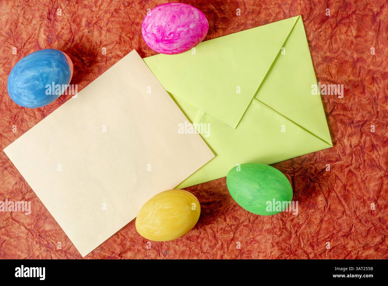 Oeufs de Pâques multicolores avec une enveloppe verte et une carte vierge symbolisant la célébration, la créativité et la communication. Banque D'Images Oeufs de Pâques multicolores avec une enveloppe verte et une carte vierge symbolisant la célébration, la créativité et la communication. Banque D'Images