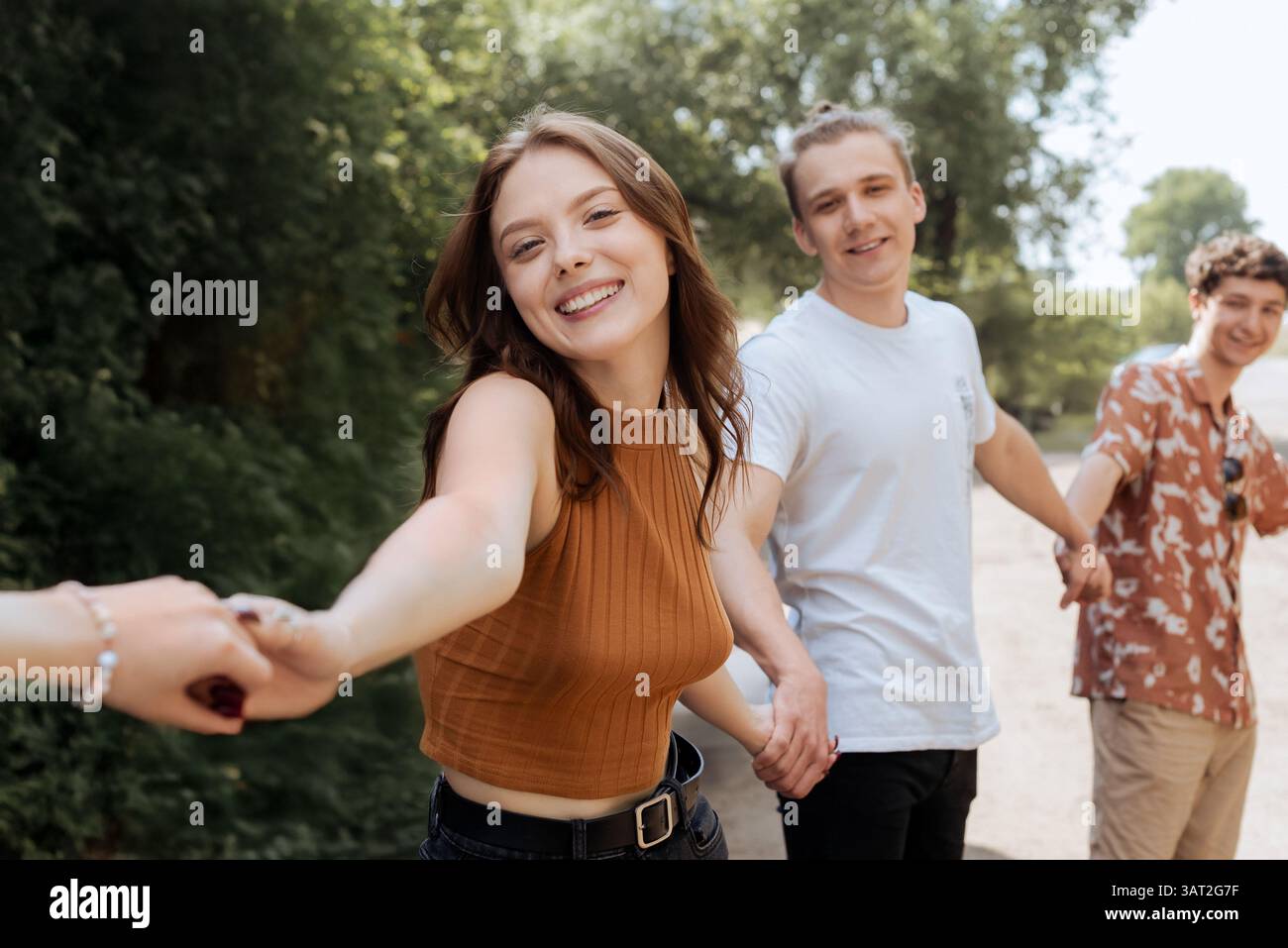 Heureux jeunes amis tenant la main dans le parc d'été Banque D'Images