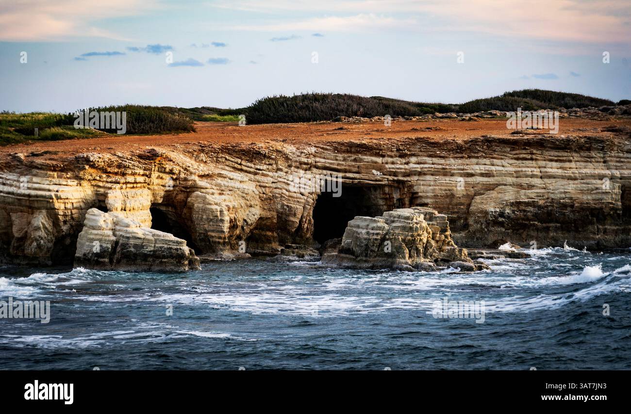 Paysage côtier rocheux avec des grottes marines et des vagues s'écrasant contre le rivage. Banque D'Images